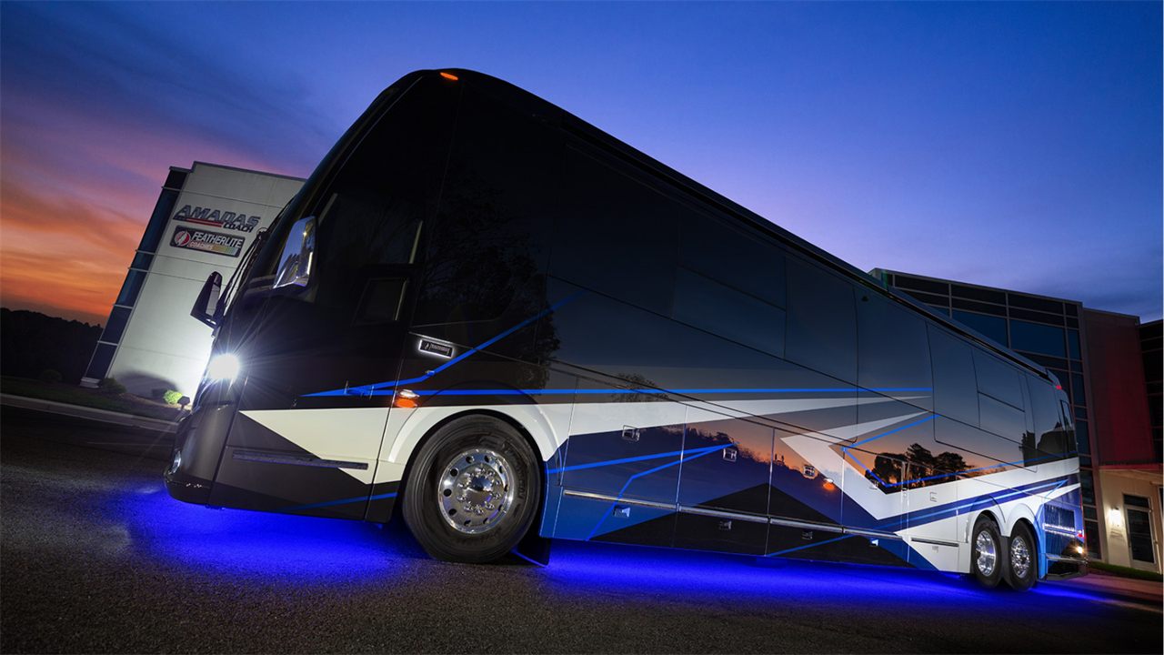 A Featherlite Vantare motorhome on a Prevost shell, lit at dusk